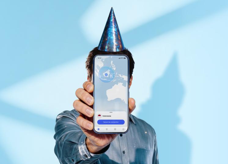 Seseorang dengan topi ulang tahun memegang ponsel yang menampilkan layar utama aplikasi NordVPN.