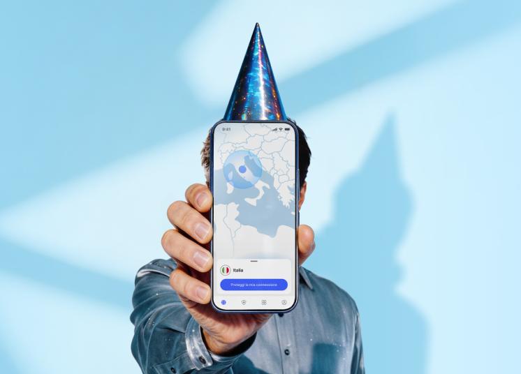 Una persona con un cappellino da festa di compleanno con in mano uno smartphone, che mostra la schermata principale dell'app NordVPN.