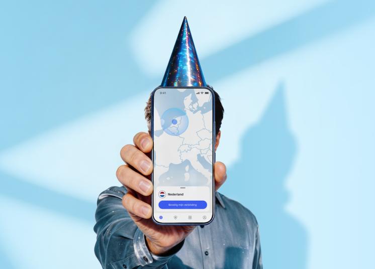 Een persoon met een verjaardagshoed die een smartphone vasthoudt waarop het hoofdscherm van de NordVPN-app te zien is.
