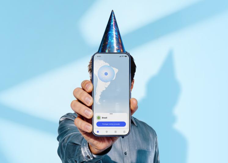 Uma pessoa com um chapéu de aniversário a segurar num smartphone que mostra o ecrã principal da aplicação NordVPN.