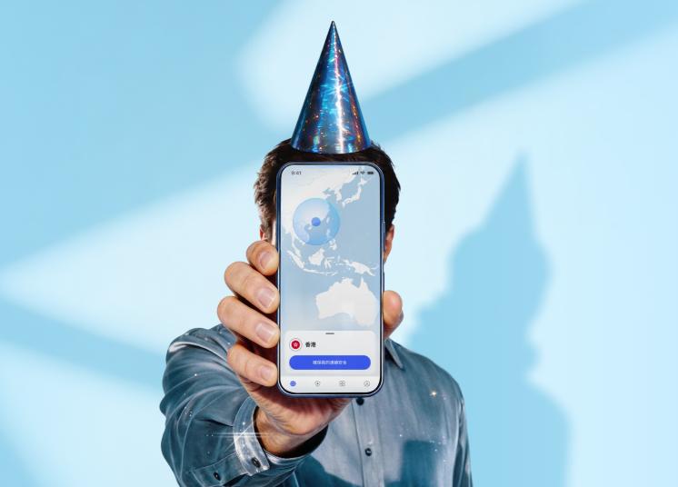 一個戴著生日帽的人拿著智能手機，手機上顯示 NordVPN 應用程式的主畫面。