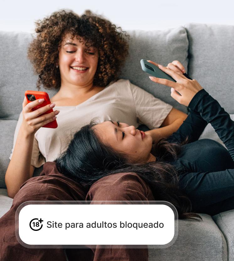Duas mulheres utilizam os seus telemóveis em segurança, enquanto a proteção contra fraudes e phishing bloqueia sites para adultos.