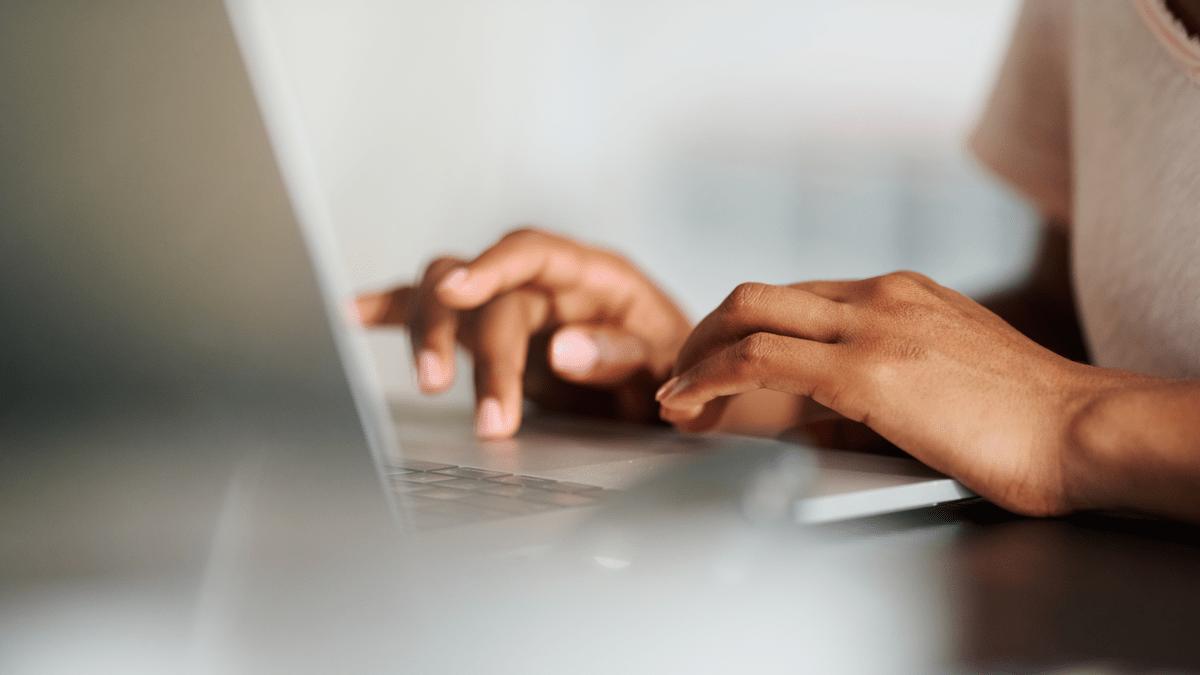 Hands typing on a laptop keyboard in warm light.