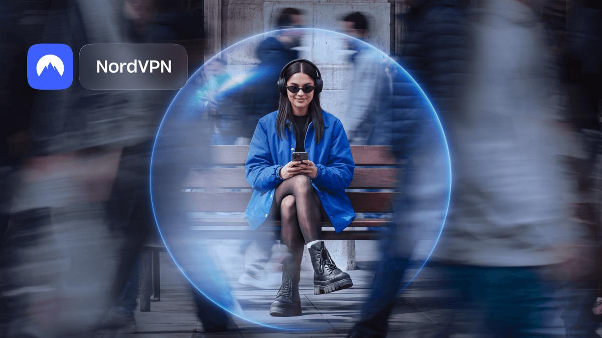 Woman in headphones sits on a bench inside a glowing blue NordVPN security bubble while blurred crowds rush past.