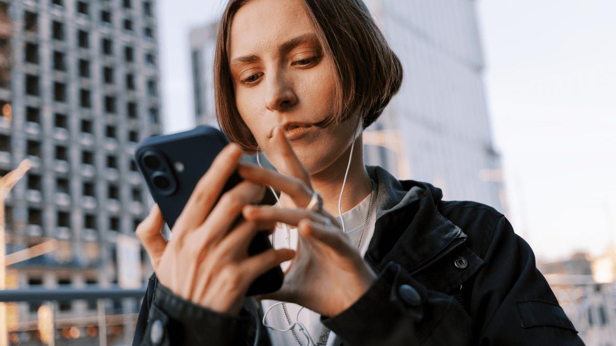 Woman using her phone with earphones on a city street.