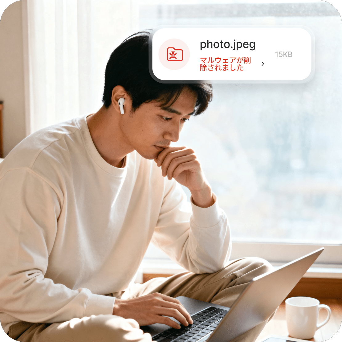 ノートパソコンを使用する男性。画面には、マルウェアが含まれていたためファイルが削除されたことを示す次世代のAVのアラートが表示されています。
