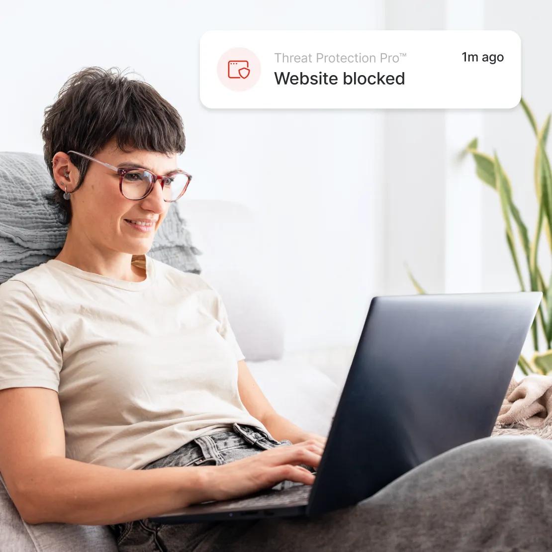 A woman enjoys safer browsing with Threat Protection Pro™ blocking malicious websites.