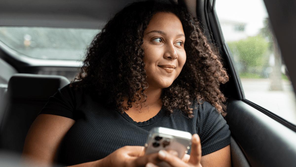 Woman using her phone in the back seat of a car.