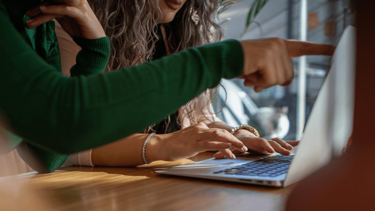 Two colleagues pointing at a laptop screen while working together.