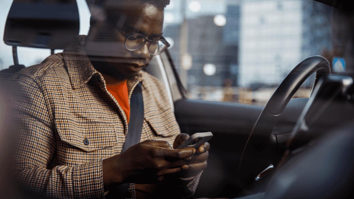 Man using his phone in the passenger seat of a car.