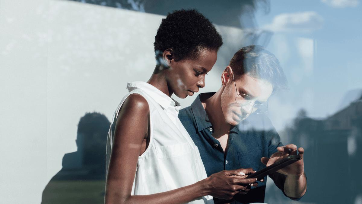 Two colleagues looking at a tablet together outdoors.