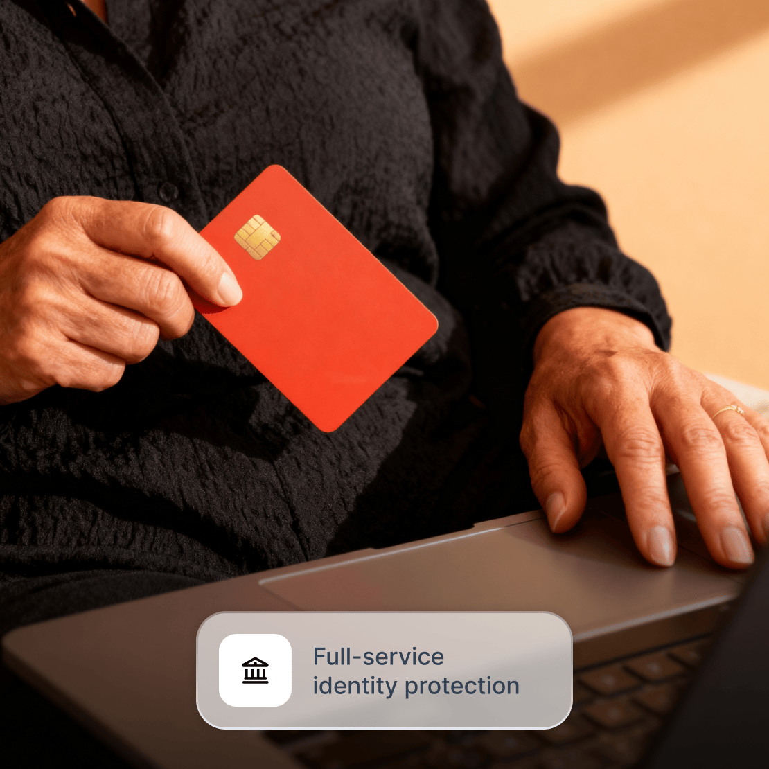 A person holding a credit card, while using Coveron on their laptop to receive online fraud insurance.