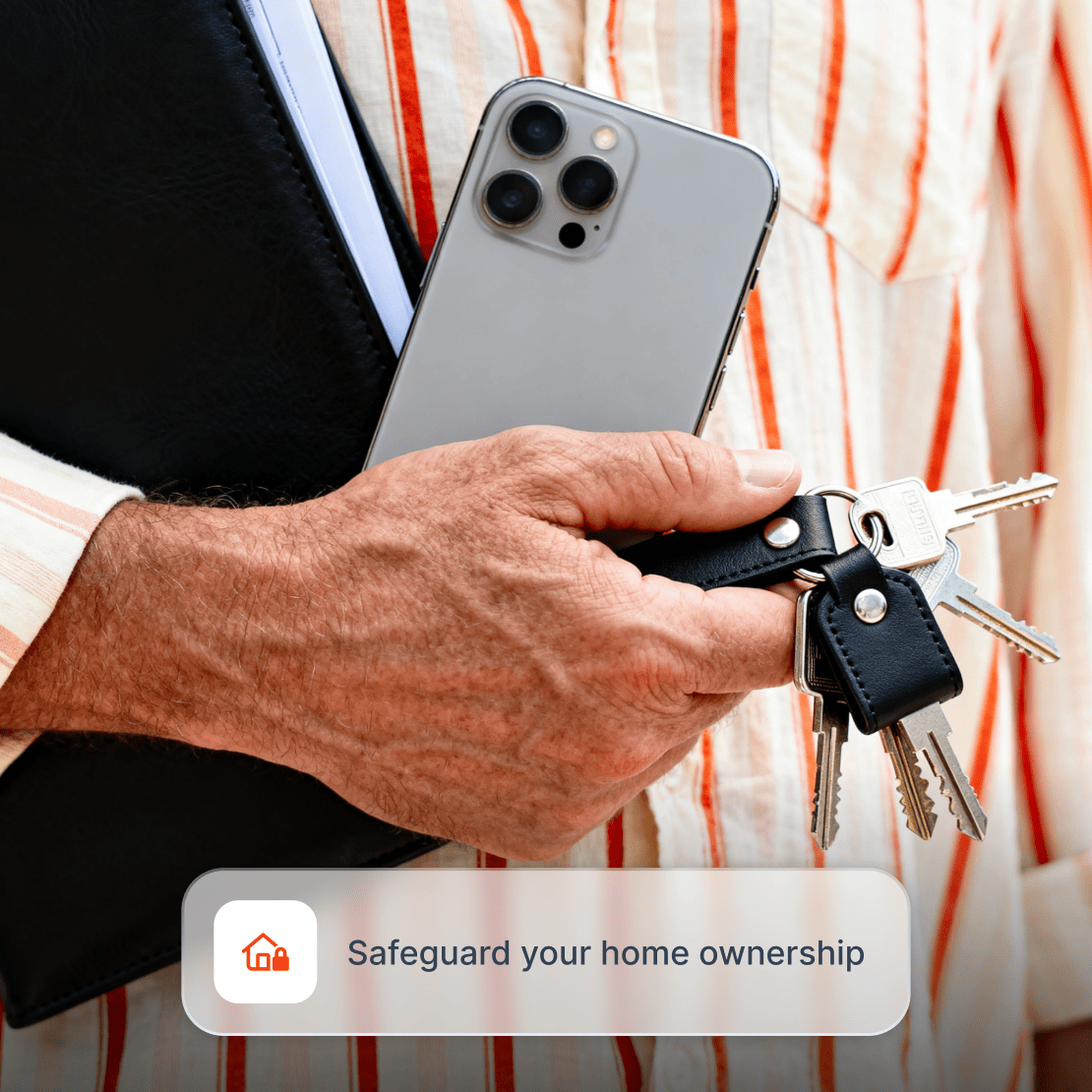 A man holds house keys and a phone, representing home title protection insurance.