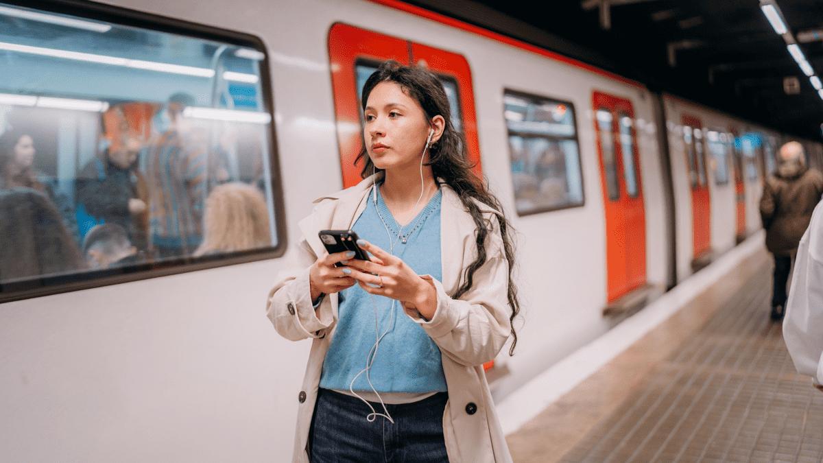 Woman holding her phone on a train platform.