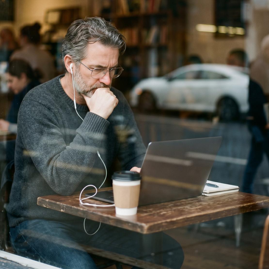 A person in a cafe setting Coveron’s cyber extortion insurance on their laptop.