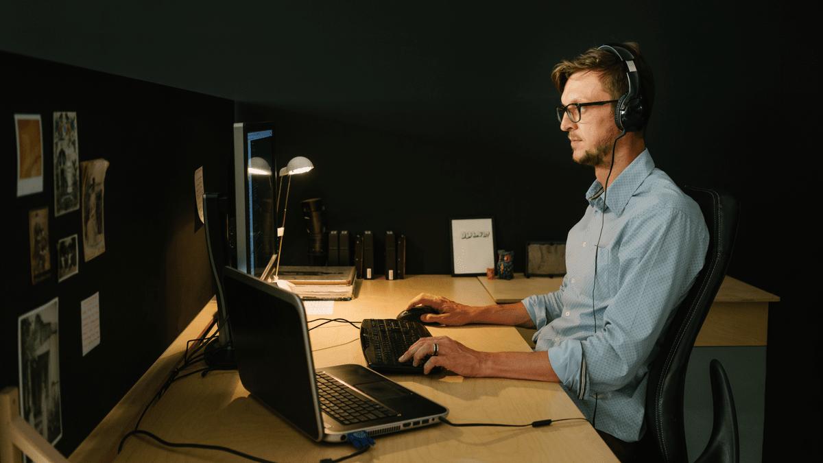 Developer working at a desk with headphones in a dark room.