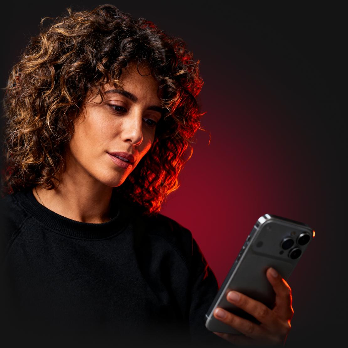 En kvinne leser om trusler på det mørke nettet på telefonen sin.