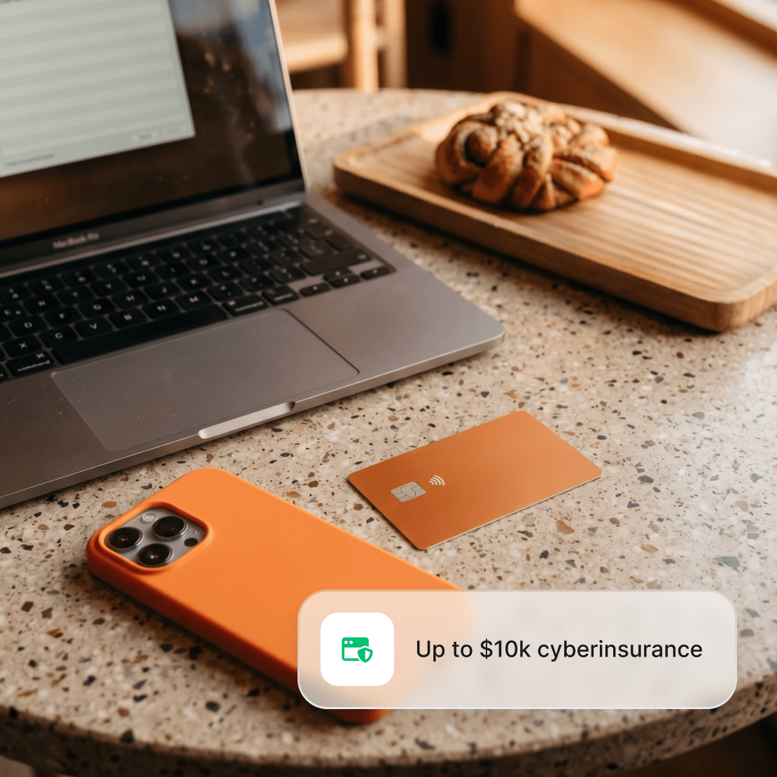A laptop, a smartphone, and a credit card lying on the table.