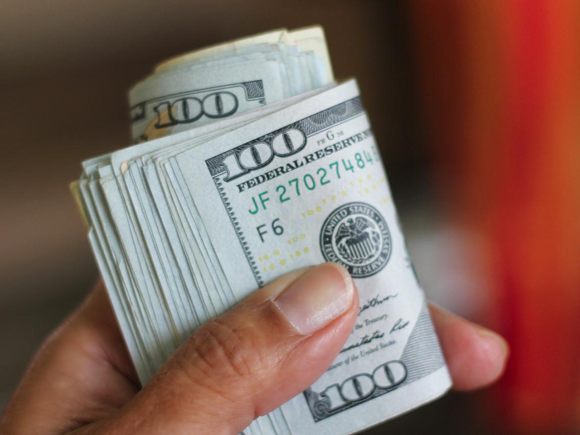 A person holds cash representing Coveron’s home title insurance reimbursement limit.