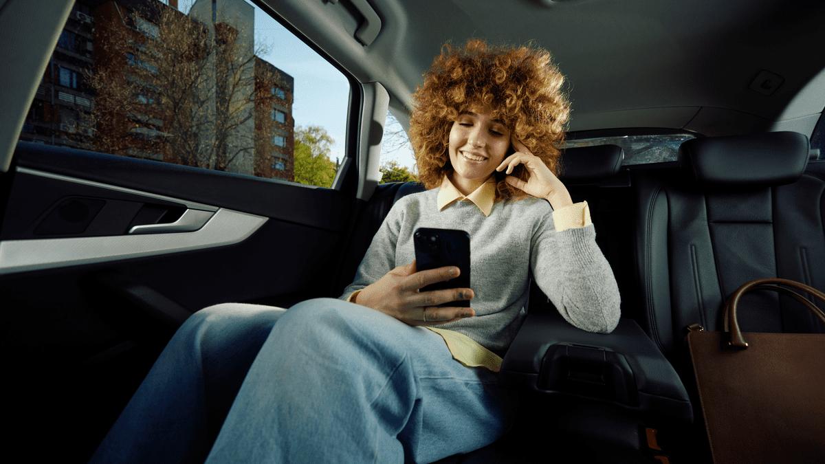 Woman using her phone in the back of a car while travelling for work.