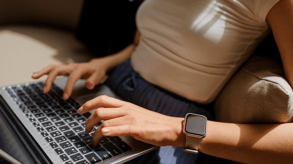 Woman using a laptop while wearing a smartwatch.