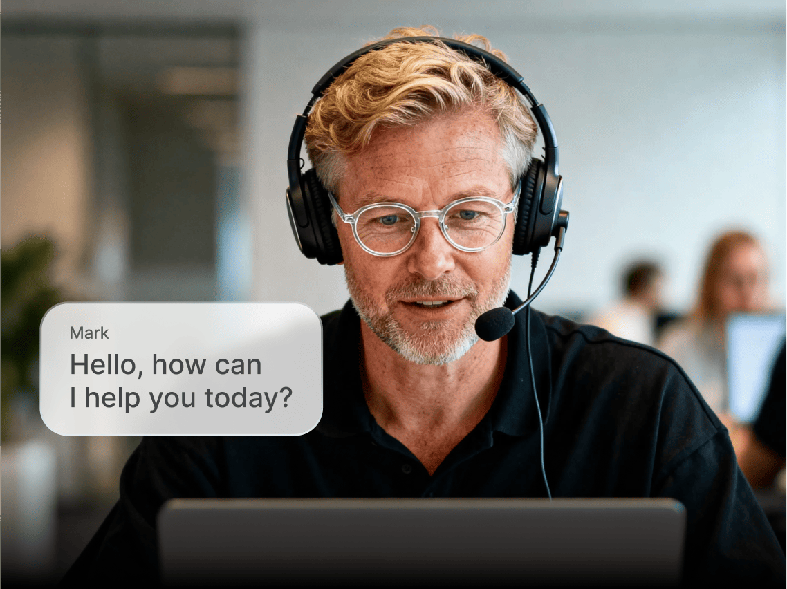 Coveron’s customer support agent wearing headphones with a microphone, looking at his laptop screen, helping the customer.