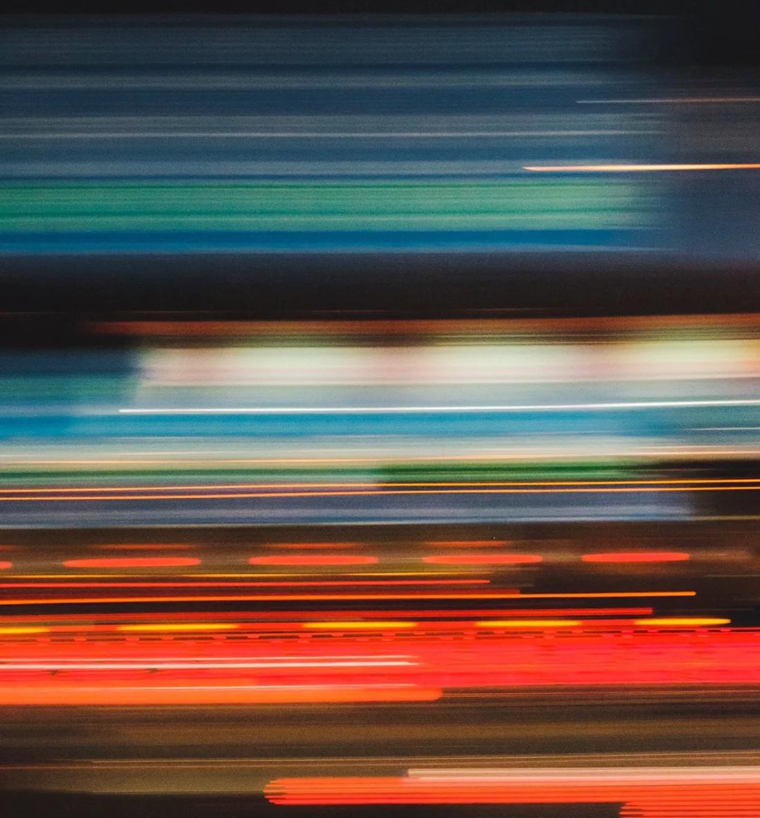 Streaking city lights at night, blurred into motion.