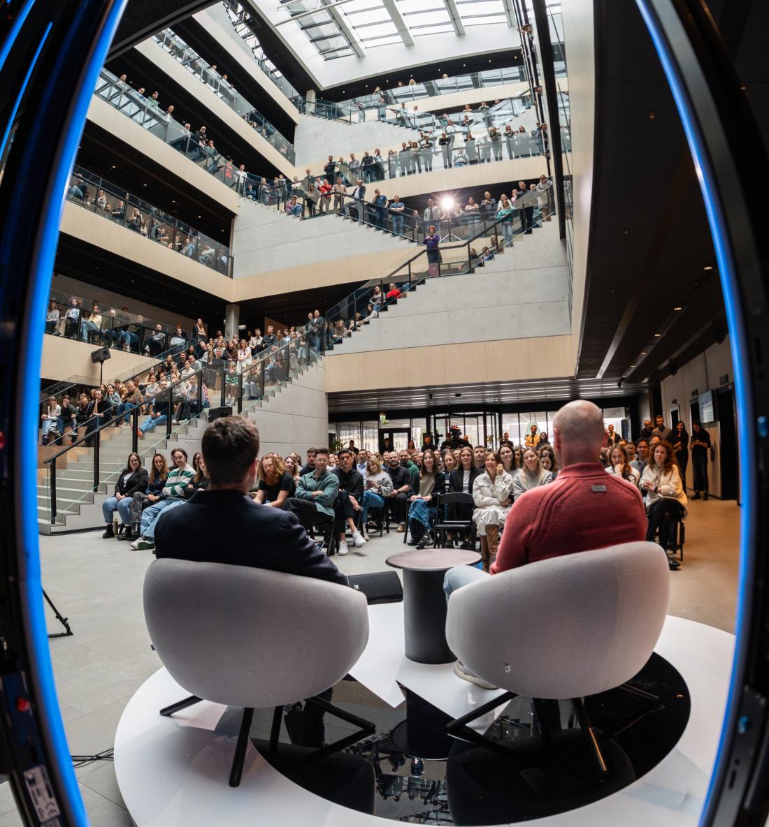 Two speakers on stage as colleagues fill the Nord Security office atrium.